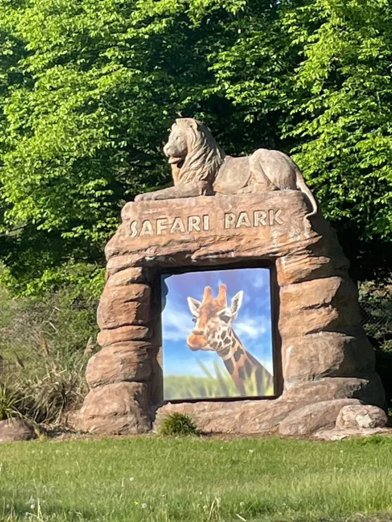 Safari Park entrance sign with a giraffe image and lion sculpture