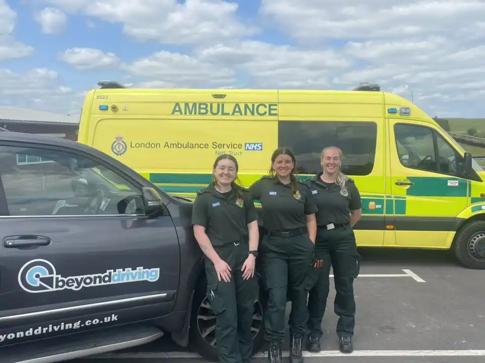 Three members of the London Ambulance Service HART team standing proudly with Beyond Driving and NHS ambulances in background