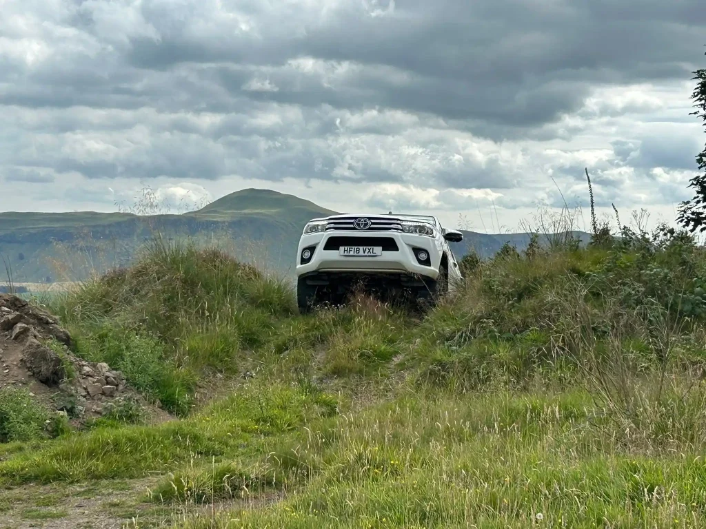 Toyota Hilux 4x4 ascending a grassy incline during off-road driver training in Fife with Beyond Driving