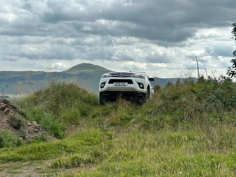 Toyota Hilux 4x4 ascending a grassy incline during off-road driver training in Fife with Beyond Driving