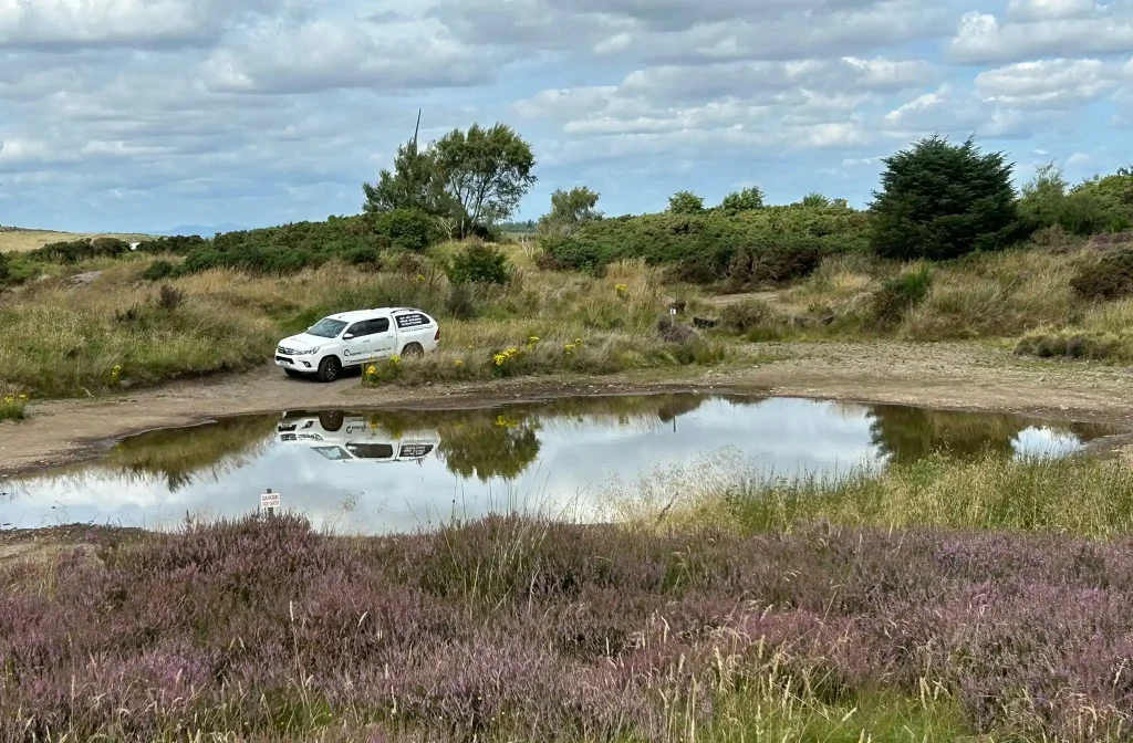 White Beyond Driving pickup reflected in off-road water obstacle at Fife training site in Scotland