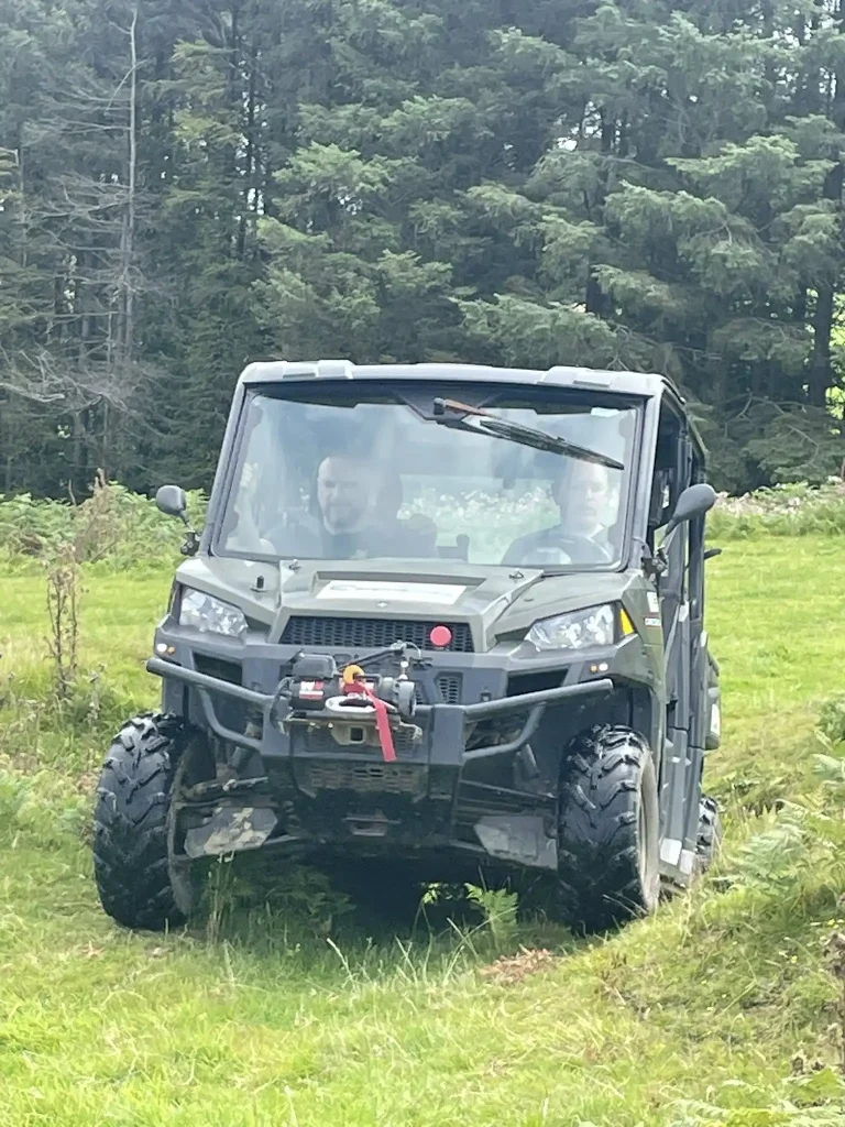 Welsh HART team member training in Polaris UTV under instructor supervision on grassy terrain