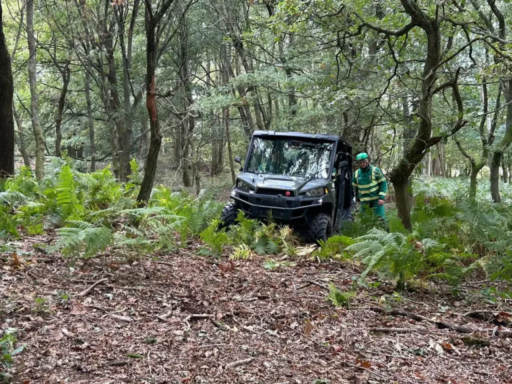 NHS HART team member standing beside Polaris UTV during winch training in woodland terrain