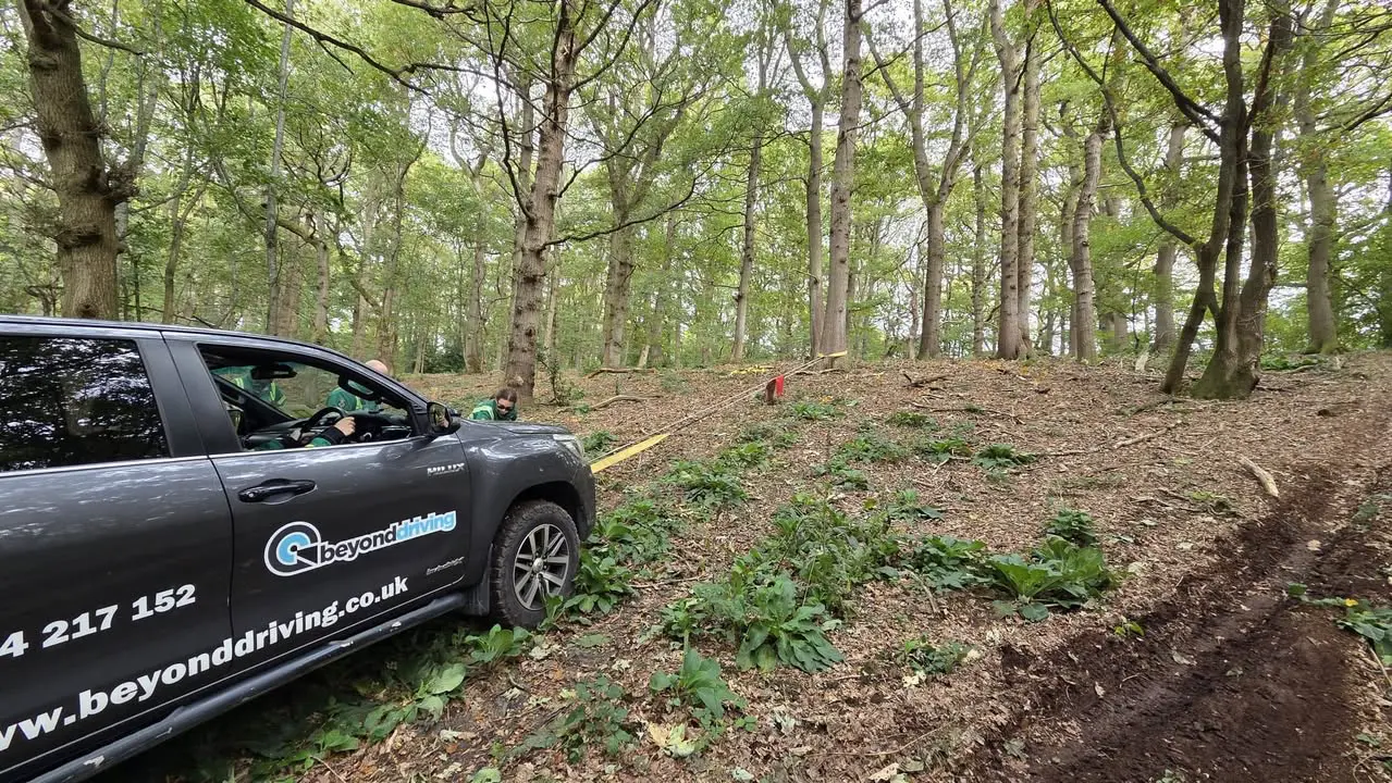 Beyond Driving 4x4 vehicle using winch for off-road recovery training in forest with tree anchor