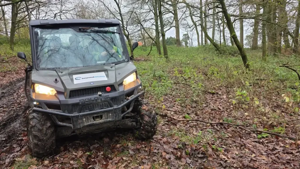 Polaris UTV manoeuvring through muddy woodland during Lantra UTV operator course.