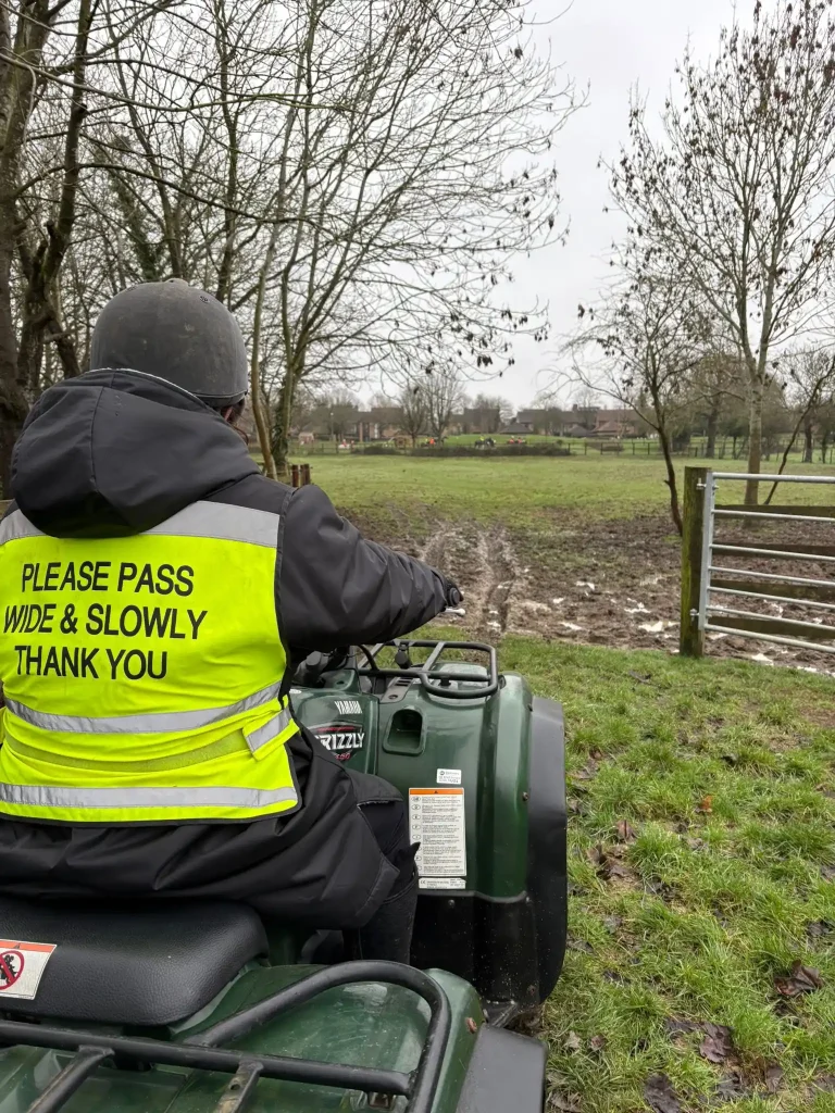 Lantra quad bike training at equestrian centre with operator assessing muddy field conditions before riding
