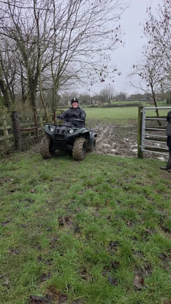 Lantra ATV operator manoeuvring quad bike safely through muddy gateway during equestrian centre training