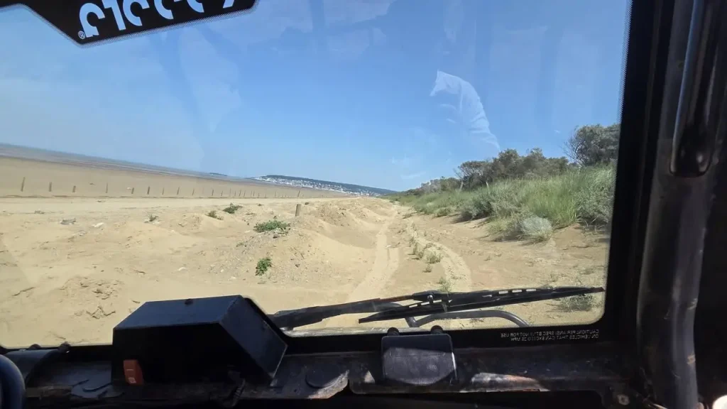 View from inside a UTV during sand driving training on a coastal beach route