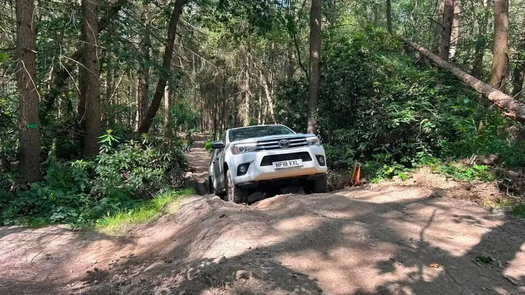 Toyota Hilux driving along a rutted forest track during professional off-road training