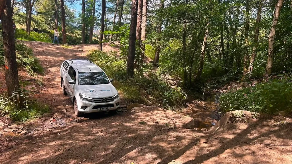 Beyond Driving Toyota Hilux negotiating rocky woodland terrain during Lantra 4×4 training near Bradford